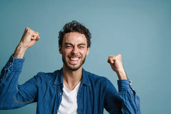 Mutlu Genç Adam Başarıyı Mavi Arka Planda Kutluyor Kameraya Bakıyor — Stok fotoğraf