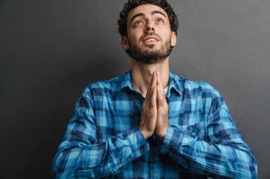 Traşsız yakışıklı, avuçlarıyla poz veren, gri arka planda soyutlanmış yakışıklı bir adam.