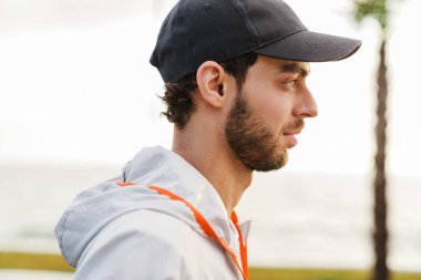 Tıraşsız sporcu gezinti güvertesinde çalışırken ileriye bakıyor.