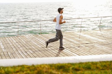 Gezinti güvertesinde koşarken odaklanmış traşsız bir adam.