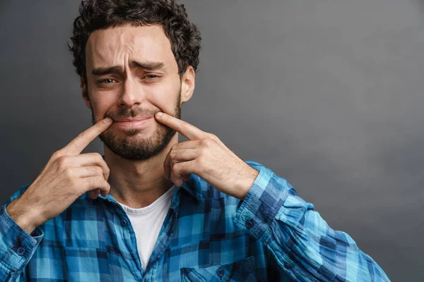 Ongelukkige Knappe Jongen Maken Glimlach Zijn Gezicht Met Vingers Geïsoleerd — Stockfoto