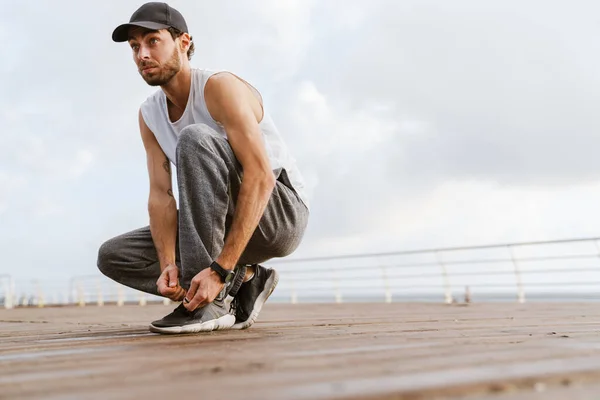 Concentrato Unshaven Ragazzo Legando Lacci Delle Scarpe Mentre Allena Sul — Foto Stock