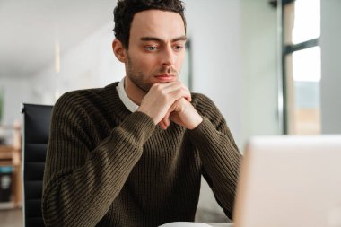 Bir ofiste dizüstü bilgisayar ve belgelerle çalışan girişimci