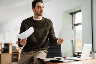 Ofiste çalışan kendinden emin genç bir yönetici, elinde belgeler var.