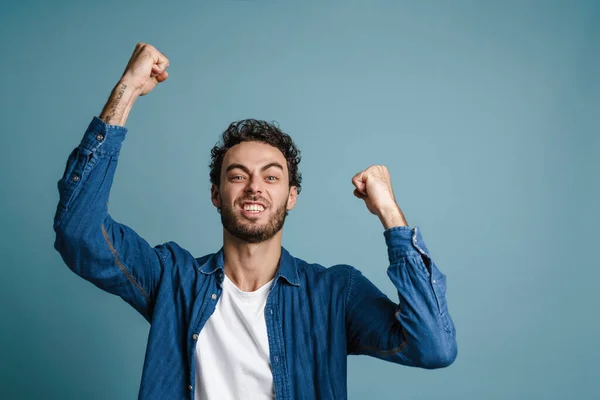 Feliz Joven Celebrando Éxito Sobre Fondo Azul Mirando Cámara —  Fotos de Stock