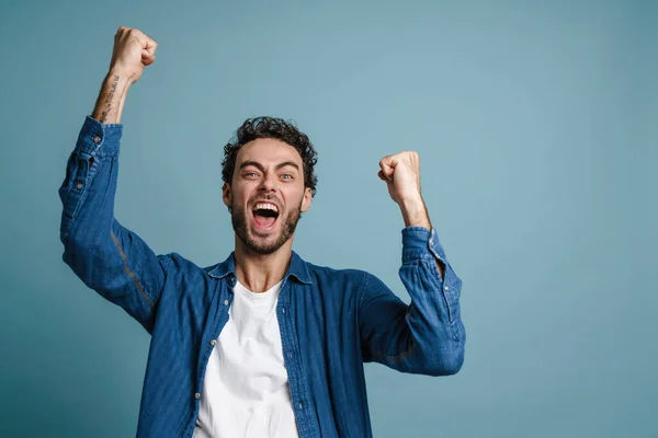 Mutlu Genç Adam Başarıyı Mavi Arka Planda Kutluyor Kameraya Bakıyor — Stok fotoğraf