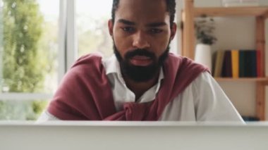 Sakin bir Afrikalı Amerikalı ofiste çalışırken dizüstü bilgisayarını kullanıyor.