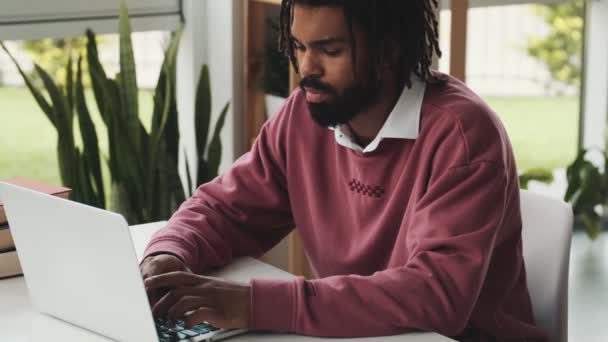 一位专心致志的非洲裔美国人坐在办公室的笔记本电脑上打字 — 图库视频影像