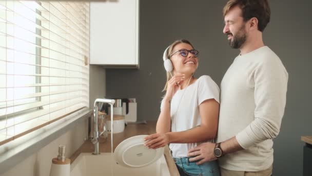 Hombre Sonriente Está Abrazando Novia Mientras Ella Lava Los Platos — Vídeos de Stock