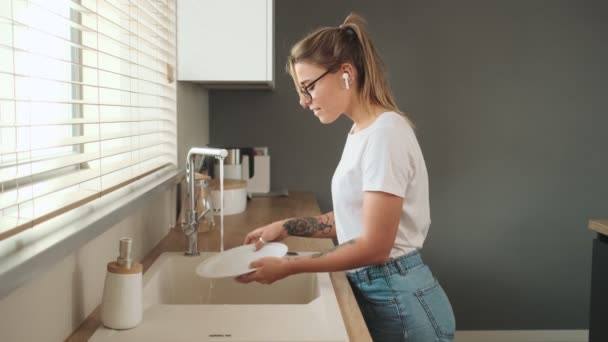 一个跳舞的女人要在家里一边洗碗一边听音乐 — 图库视频影像