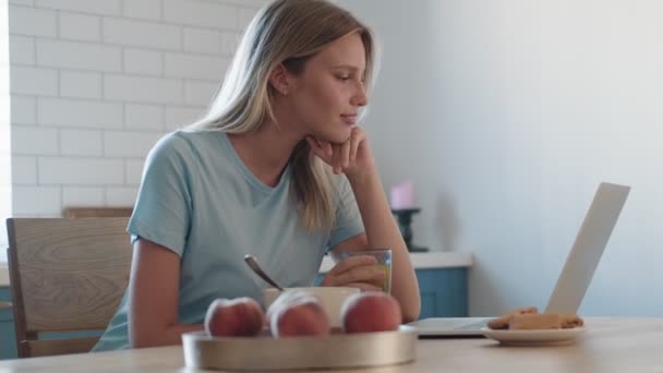 Een Tevreden Vrouw Zit Thuis Ontbijten Terwijl Naar Haar Laptop — Stockvideo