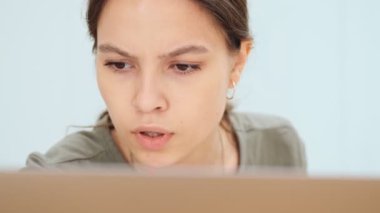 Ciddi bir kadının yakın plan görüntüsü ofiste otururken dizüstü bilgisayar kullanıyor.