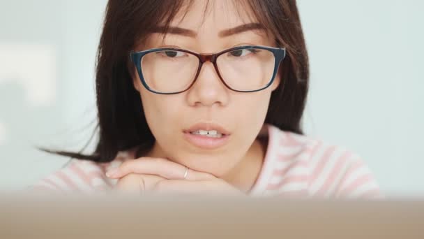 アジア系の深刻な女性のクローズアップは オフィスでラップトップコンピュータを使用しています — ストック動画