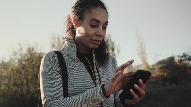 Uma Bela Jovem Afro Americana Está Usando Telefone Enquanto Caminha — Vídeo de Stock