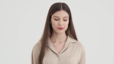 Güzel görünümlü, kendine güvenen genç bir kadın, stüdyoda beyaz arka planda izole bir şekilde duruyor.