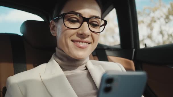 Uma Jovem Empresária Satisfeita Usando Óculos Está Usando Seu Telefone — Vídeo de Stock