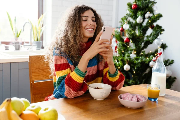 Χαρούμενη Γοητευτική Γυναίκα Που Χρησιμοποιεί Κινητό Τηλέφωνο Ενώ Έχοντας Πρωινό — Φωτογραφία Αρχείου