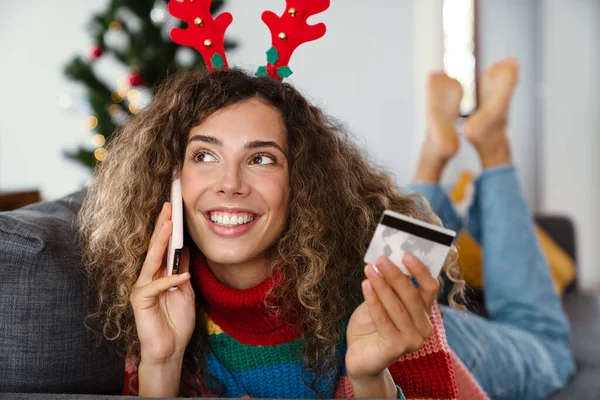 Mulher Feliz Falando Celular Segurando Cartão Crédito Enquanto Deitado Sofá — Fotografia de Stock