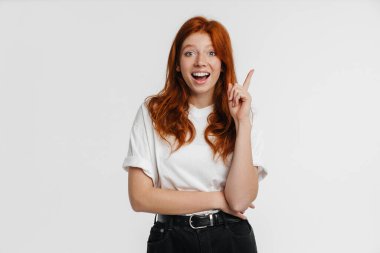 Ginger güzel heyecanlı kız beyaz arka planda dışlanmış bir şekilde işaret ediyor.