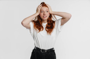 Ginger güzel memnun kız poz veriyor ve başını tutuyor beyaz arka planda izole edilmiş.