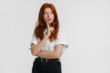 Kızıl, güzel, mutsuz, poz veren, beyaz arka planda yalnız bir kız.