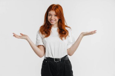 Ginger güzel neşeli kız gülümsüyor ve beyaz arkaplanda izole edilmiş bir telif alanı tutuyor.