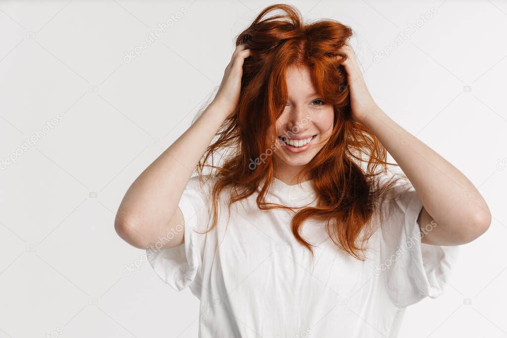 Ginger beautiful happy girl smiling and making fun with her hair isolated over white background