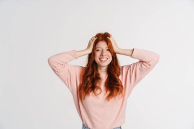 Ginger güzel mutlu kız başını tutuyor ve gülümsüyor beyaz arka planda.