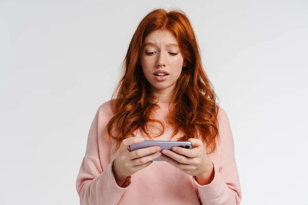 Рыжая Красивая Целеустремленная Девушка Играет Онлайн Игру Мобильном Телефоне Изолированы — стоковое фото