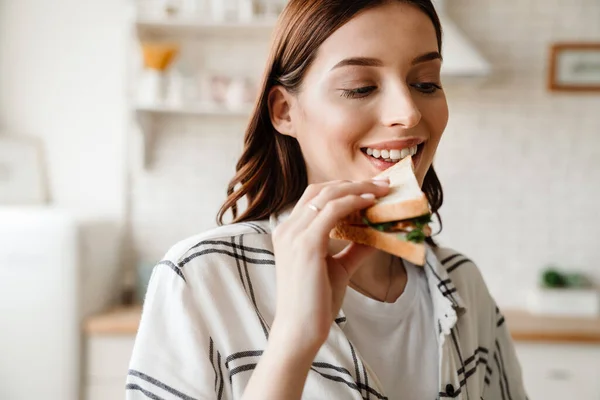 Mooie Gelukkig Vrouw Glimlachen Tijdens Het Eten Sandwich Huis Keuken — Stockfoto