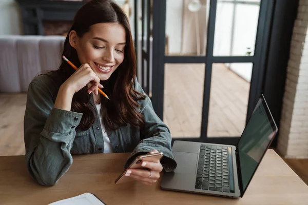 Hermosa Mujer Sonriente Usando Teléfono Celular Mientras Trabaja Con Ordenador —  Fotos de Stock