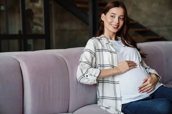 Ευτυχισμένη Γοητευτική Έγκυος Γυναίκα Χαμογελώντας Και Κάθεται Στον Καναπέ Στο — Φωτογραφία Αρχείου