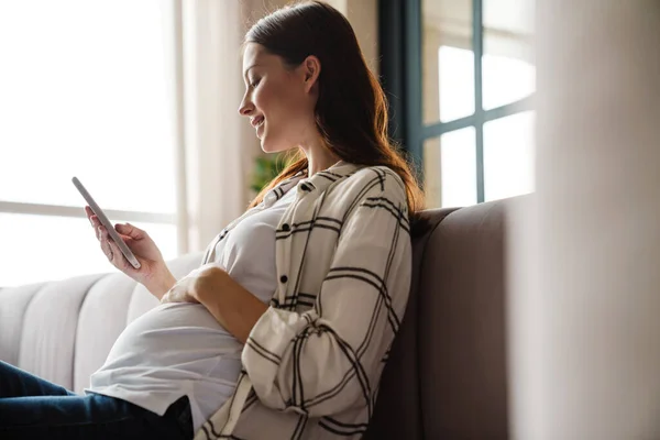 Feliz Mujer Embarazada Encantadora Usando Teléfono Móvil Mientras Está Sentado — Foto de Stock