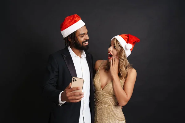 Счастливая Веселая Пара Рождественских Шляпах Помощью Мобильного Телефона Изолированы Черном — стоковое фото