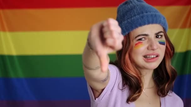 Een Ongelukkige Jonge Vrouw Toont Duimgebaar Geïsoleerd Boven Regenboogvlag — Stockvideo