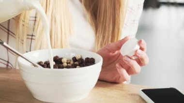 Sarışın genç bir kadının yakın çekim görüntüsü evdeki mutfakta kahvaltı hazırlıyor.