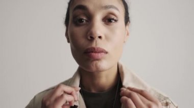 Sakin, genç bir Amerikan askerinin yakın plan görüntüsü stüdyodaki gri arka planda tek başına duran elbiselerini düzeltiyor.