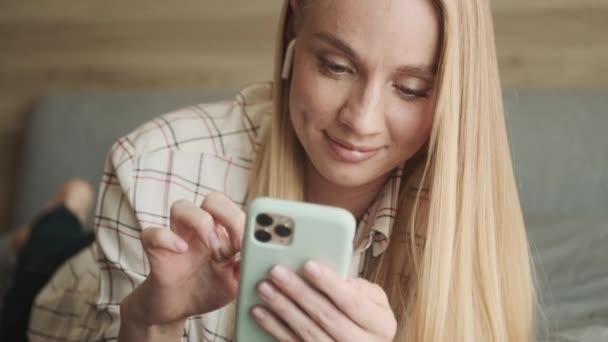 Uma Jovem Loira Calma Positiva Está Usando Seu Smartphone Quarto — Vídeo de Stock