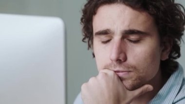 Uykulu yorgun bir işadamı ofiste otururken bilgisayarla çalışıyor.