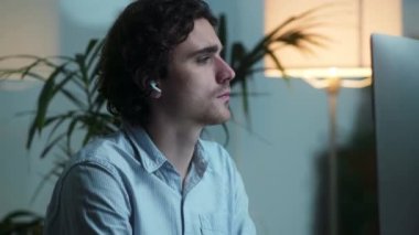 Kulaklık takan odaklanmış bir işadamı ofisinde bilgisayarıyla çalışıyor.