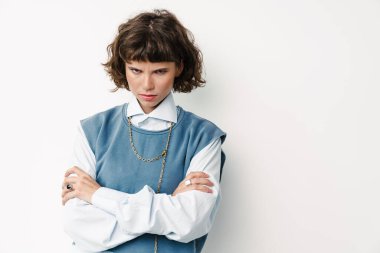 Hoş olmayan güzel kız kollarını kavuşturup beyaz arka planda yalnız poz veriyor.