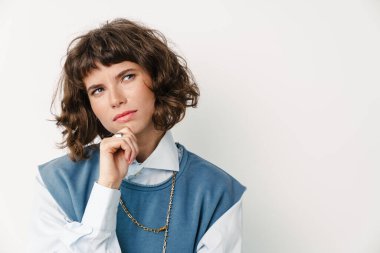 Ciddi, güzel bir kız beyaz arka planda izole edilmiş bir şekilde düşünüyor.