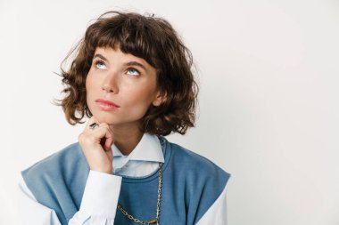 Beyaz arka planda, beyaz tenli güzel bir kız poz veriyor ve yukarı bakıyor.