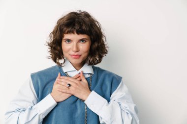 Mutlu güzel kız, elleri göğsünde poz veriyor, beyaz arka planda soyutlanmış.