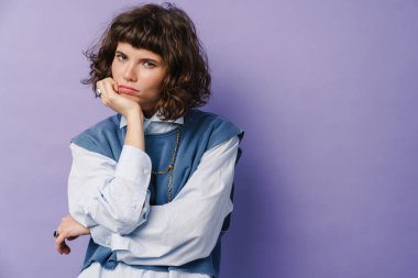 Ciddi, güzel bir kız. Mor arka planda izole edilmiş kameraya bakıyor.