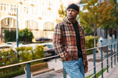 Kendine güvenen, şık, Afro-Amerikan bir adam sokakta yürüyor.