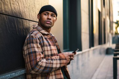 Sokakta cep telefonuyla yürüyen çekici, kendine güvenen bir Afrikalı.