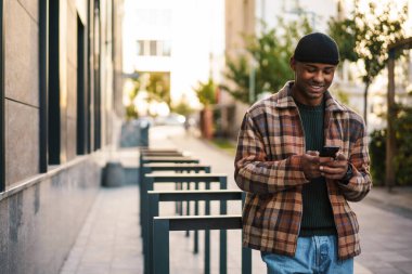 Sokakta cep telefonuyla yürüyen çekici, kendine güvenen bir Afrikalı.