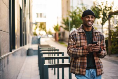 Sokakta cep telefonuyla yürüyen çekici, kendine güvenen bir Afrikalı.
