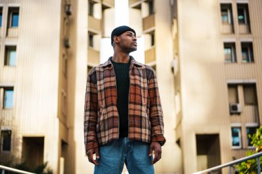 Kendine güvenen, şık, Afro-Amerikan bir adam sokakta yürüyor.